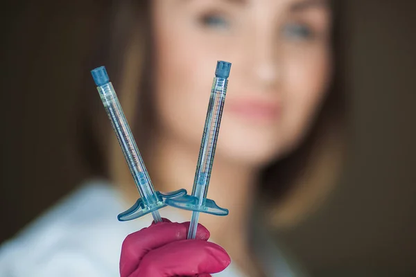 Şırıngaları olan çekici genç bir doktor. Tıbbi aletler tutan kozmetolojistin yakın plan portresi. Klinikteki ya da hastanedeki doktor. Hemşire iğne yapacak..