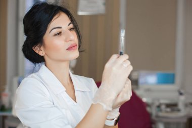 Şırıngaları olan çekici genç bir doktor. Tıbbi aletler tutan kozmetolojistin yakın plan portresi. Klinikteki ya da hastanedeki doktor. Hemşire iğne yapacak..