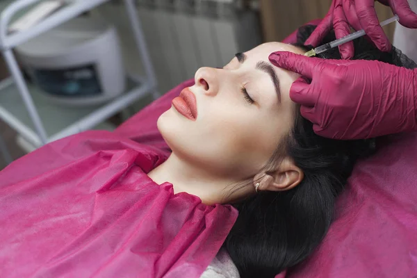 Cosmetologist making procedure. Dermatologist making an injection of hyaluronic acid. Close up still of lip injection. Lip booster procedure. Beauty salon service.
