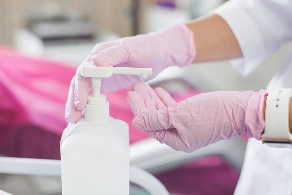 Unrecognizable doctor cleaning and disinfecting hands. Antibacterial agent in the hands close up. Cosmetologist disinfecting her hands in latex gloves before prosedure.