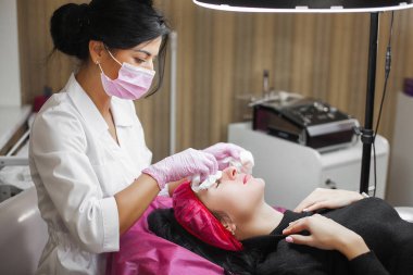 Kozmetolojist yüz bakımı prosedürü yapıyor. Müşterisine yüz maskesi uygulayan uzman. Dermatoloji tedavisi. Yüz soyma. 
