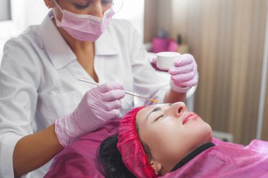 Kozmetolojist yüz bakımı prosedürü yapıyor. Müşterisine yüz maskesi uygulayan uzman. Dermatoloji tedavisi. Yüz soyma. 