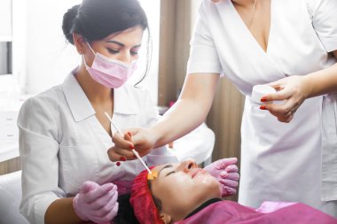 Cosmetologist making a face massage to her patient and a face mask. Anti-ageing and smoothing procedure in a beauty salon. Doctor in a cosmetological clinic making a treatment of skin care clipart
