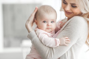 Genç çekici kaygı-in küçük bebek kızı anne. Güzel anne ve kızı yatak odasında kapalı. Sevgi dolu aile. Çekici anne çocuğunu tutan.