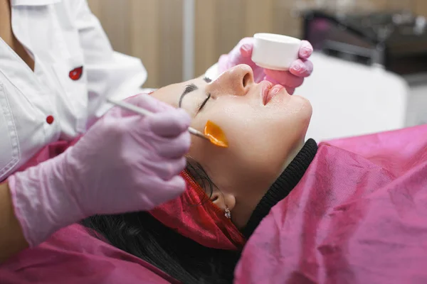 Cosmetologist making a face massage to her patient and a face mask. Anti-ageing and smoothing procedure in a beauty salon. Doctor in a cosmetological clinic making a treatment of skin care