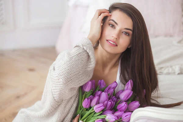 迷人的年轻女子与鲜花在室内的卧室 美丽的女士的肖像在家里 用郁金香近距离拍摄女性 — 图库照片