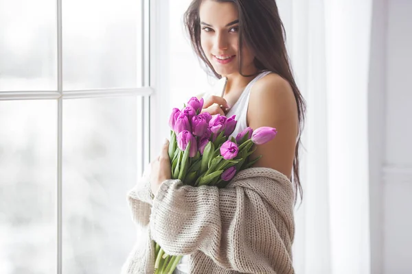 迷人的年轻女子与鲜花在室内的卧室 美丽的女士的肖像在家里 用郁金香近距离拍摄女性 — 图库照片