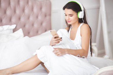 Müzik genç çekici kadın duyuyor. Çekici kız kulaklık. Kadın kapalı içinde yatak rahatlatıcı. Kulaklık giyen Bayan.