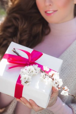 Bahar hediyesi ya da hediyesi olan tanınmayan genç kadın. Bahçede doğal bahar arka plan açık havada güzel bayan.