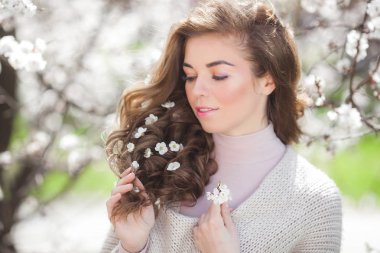 Bahar arka plan üzerinde açık genç çekici kadın Closeup güzellik portresi. Sarı saçında çiçekler olan gülümseyen bir kız. Kıvırcık saçlı kadın.
