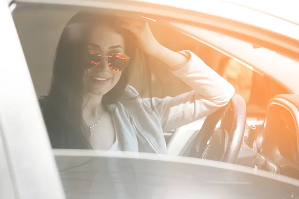 Confident woman in automobile. Lady driving a car. Young beautiful female sitting in the auto. Urban woman.