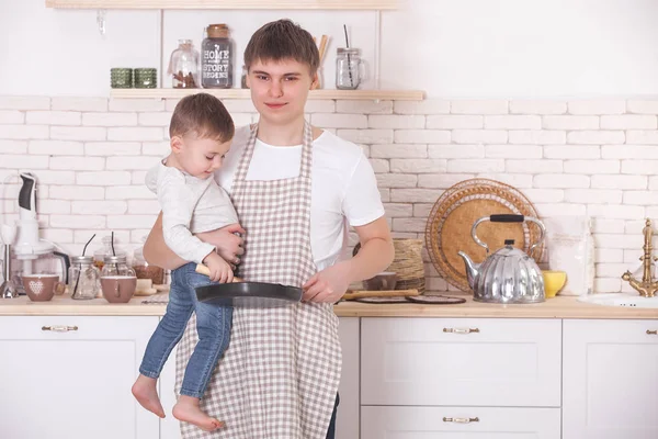 Young father cooking with his little son. Dad and child on the kitchen. Mothers day helpers. Man with kid making a dinner or breakfast for the mother.