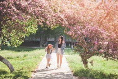 Genç çekici anne ve küçük kızı birlikte eğleniyor arka plan bahar. Çıtır kızlar. Aile açık havada. Yaz ruh hali.