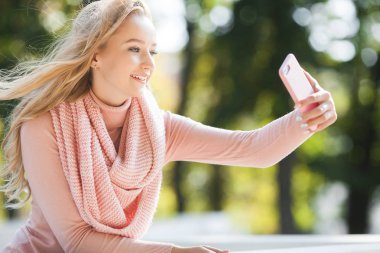 Genç kız selfie çekiyor ve cep telefonuyla konuşuyor. Cep telefonu olan çekici bir kadın. Akıllı telefondan resim yapan bir kadın..