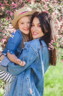 Genç çekici anne ve küçük kızı birlikte eğleniyor arka plan bahar. Çıtır kızlar. Aile açık havada. Yaz ruh hali.