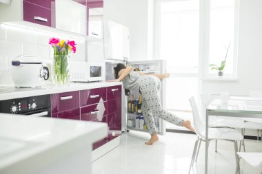 Diyet dolandırıcısı. Buzdolabının yanındaki mutfakta bir kadın. Kadın yemek istiyor. Sabah aç bayan.