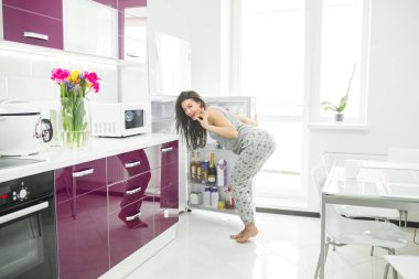 Diyet dolandırıcısı. Buzdolabının yanındaki mutfakta bir kadın. Kadın yemek istiyor. Sabah aç bayan.