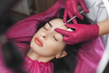 Cosmetologist making an ingection to her client. Woman beauty procedure, lip augmentation procedure. Antiageing treatment. clipart