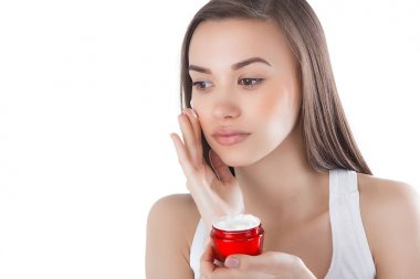 Yüz kremi süren genç ve güzel bir kadın. İzole edilmiş beyaz arka planda bir kadın. Yüz bakımı. Çekici bir bayanın yüz resmi..