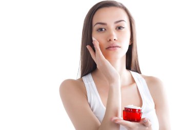 Yüz kremi süren genç ve güzel bir kadın. İzole edilmiş beyaz arka planda bir kadın. Yüz bakımı. Çekici bir bayanın yüz resmi..