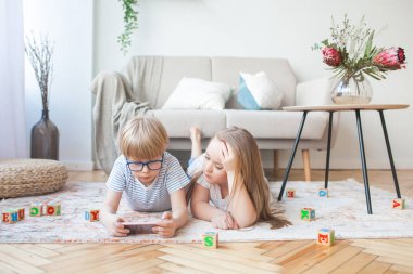 Akıllı telefon oynayan iki çocuk. Evde ki erkek ve kız cep telefonunu izliyorlar. Dijital çocuklar kapalı.