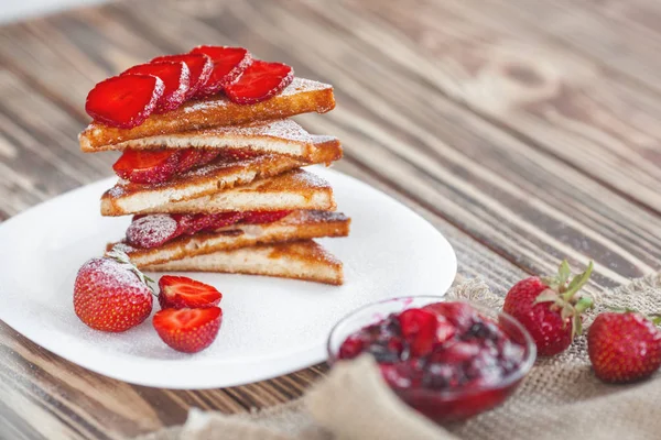 Morning breakfast. Toasts with strawberry and jam. Bread and confiture. Fresh hot toasts with cream. Delicious homemade dessert.