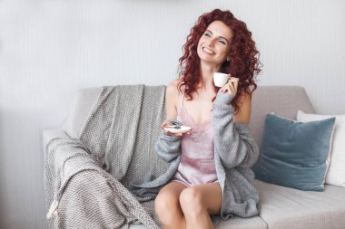 Sabahları kahve ya da çay içen çekici genç bir kadın. Mutlu kadın hafta sonları uyanıyor. Evdeki güzel bayan..