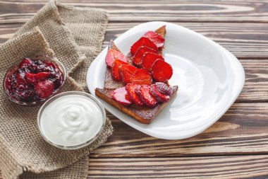 Sabah kahvaltısı. Çilek ve reçel ile tost. Ekmek ve sırdaş. Kremalı taze sıcak tostlar. Lezzetli ev yapımı tatlı.