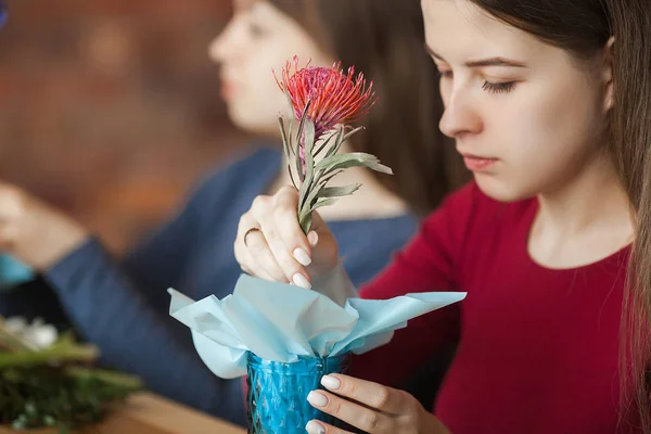 Women on the master-class on floristics. Young ladies making floral composition. Group of females with flowers indoor at the loft background. Decoration process.