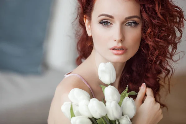 Very attractive young woman indoors. Portrait of curly haired female. Redhaired beautiful woman at home.