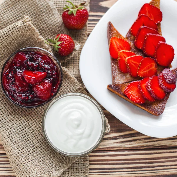 Morning breakfast. Toasts with strawberry and jam. Bread and confiture. Fresh hot toasts with cream. Delicious homemade dessert.