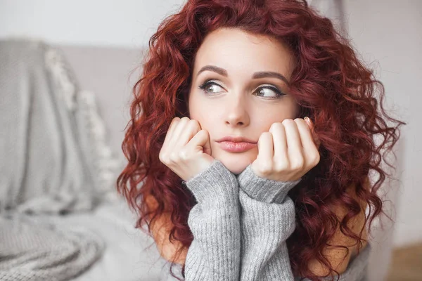 Very attractive young woman indoors. Portrait of curly haired female. Redhaired beautiful woman at home.