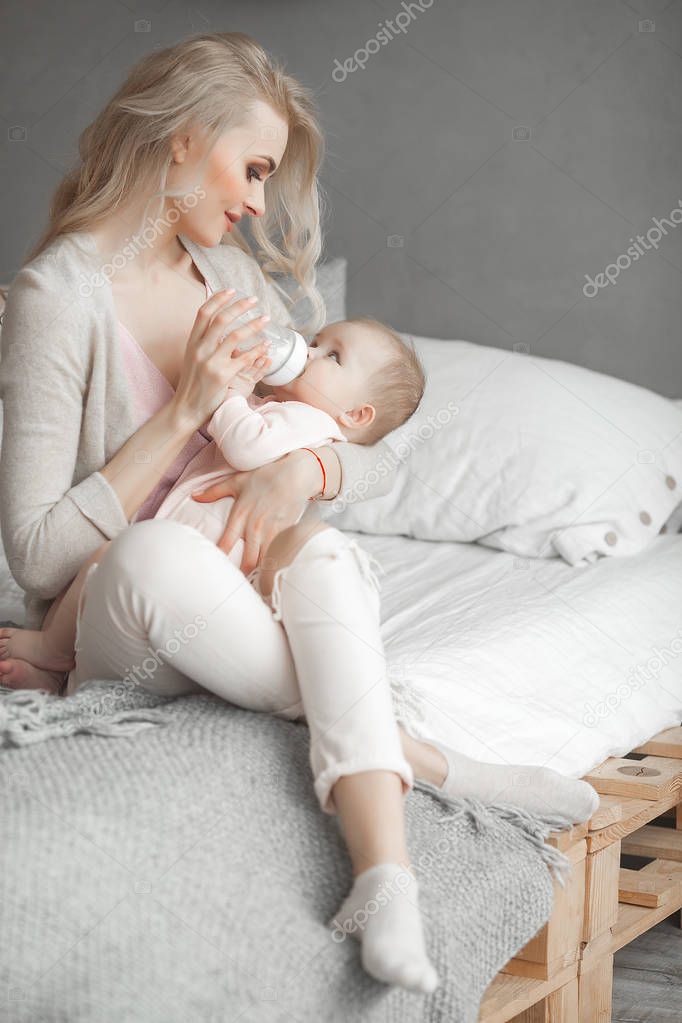 Little cute baby sucking the bottle with formula. Mothe feeding her little child with breast milk.