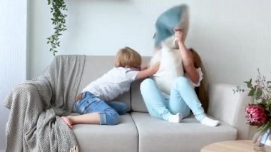 Küçük çocuklar içeride eğleniyor. Kanepede oynayan çocuklar. Yastık savaşı. Erkek ve kız kardeş evde karışıklık yapma.