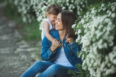 Sevimli anne ve kızı birlikte. Mutlu bir aile dışarıda. Çiçeklerdeki kızlar. Yaz arka plan üzerinde Ypung kadın ve çocuğu.