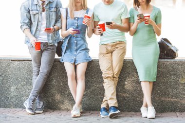 Gençler akıllı telefonda yazı yazıyor. Bir grup arkadaş cep telefonlarını izliyor. Gençlik ve dijital teknoloji.