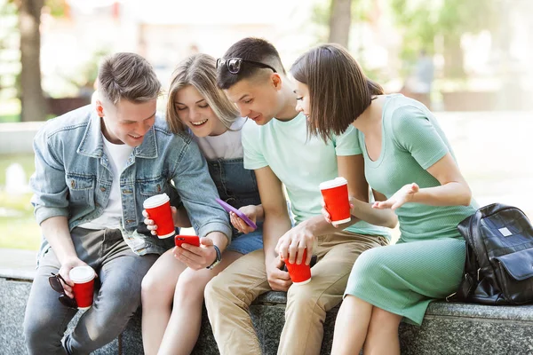 Young people typing at the smartphone. Group of friends watching at their cell phones. Youth and digital technology.