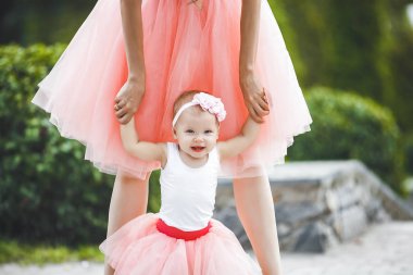 Recodnizable anne elinden onun küçük bebek kız tutarak ve yürümeye yardımcı olur. Küçük bir çocuğun ilk adımları. Yürümeye çalışan bebeğin bacakları.