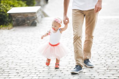 Küçük çocuğuyla dışarıda yürüyen genç bir baba. Baba kızına bakıyor. Babalar ve kızlarının sevgisi. Küçük kızını elinden tutan bir adam..