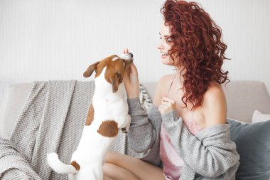 Küçük sevimli köpeğiyle oynayan genç ve çekici bir kadın. Kadın, evcil hayvanını içeride eğitiyor.. 