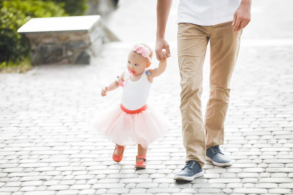 Küçük çocuğuyla dışarıda yürüyen genç bir baba. Baba kızına bakıyor. Babalar ve kızlarının sevgisi. Küçük kızını elinden tutan bir adam..
