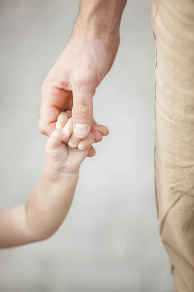 Young father walking with his little child outdoors. Dad taking care of his daughter. Father`s and daughter`s love. Man holding his little baby girl by the hand.