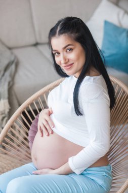 Çocuk bekleyen çekici genç bir kadın. Hamile bir kadın. İçerideki kadın karnını kucaklıyor..