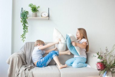 İçeride yastıklarla oynayan şirin çocuklar. Erkek ve kız kardeş birlikte eğleniyorlar. Yastık savaşı.