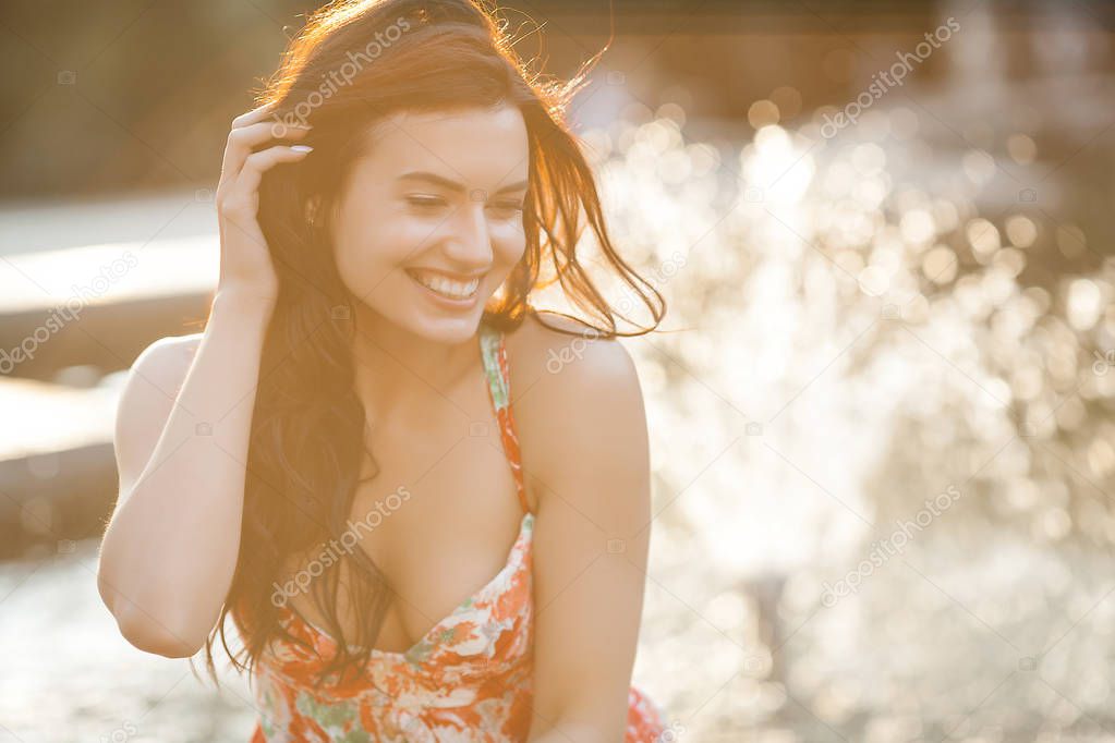 Beauty portrait of woman outdoors. Attractive stylish young female near the fountain in summertime.Closeup portrait of cheerful girl.