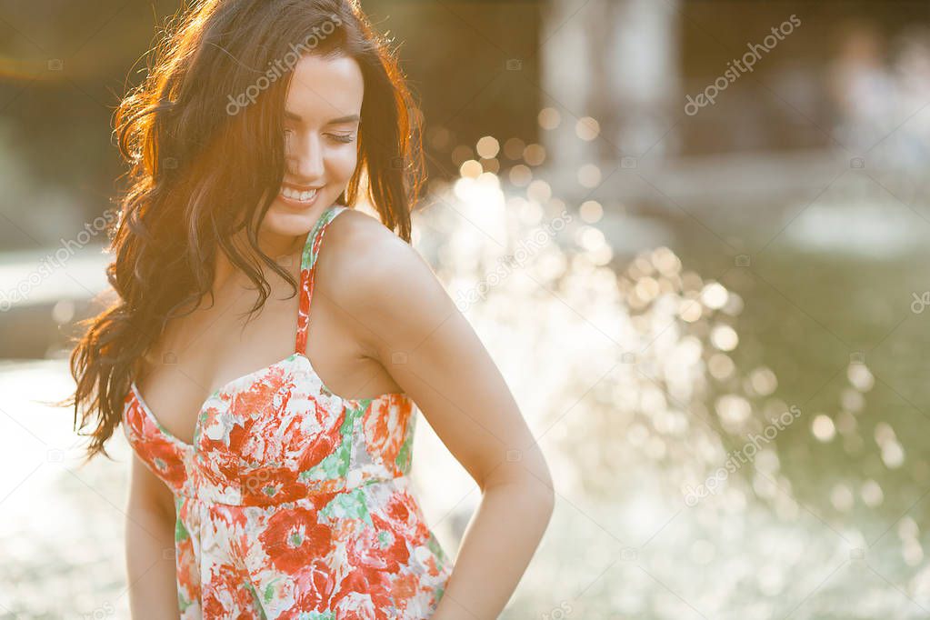 Beauty portrait of woman outdoors. Attractive stylish young female near the fountain in summertime.Closeup portrait of cheerful girl.