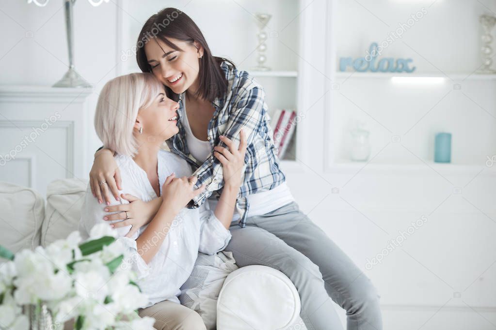 Closeup portrait of two beautiful women mom and daughter. Mid adult mother embracing her adult daughter indoors. Happy smiling females hugging.