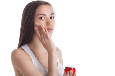 Yüz kremi uygulayan genç çekici kadının closeup portresi. Kadın nemlendirici yüz kremi ile bir kavanoz tutarak.