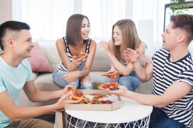 Pizza yiyen gençler. Bir grup arkadaş içeride öğle yemeği yiyor. Komik arkadaşlar birlikte..