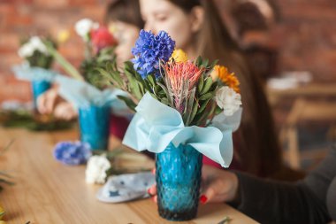 Çiçek maser sınıfı. Taze çiçeklerle çiçek kompozisyonu yapan kadınlar.